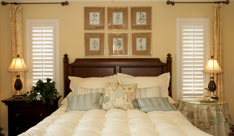Beige bedroom with white plantation shutters covering windows in Boise 